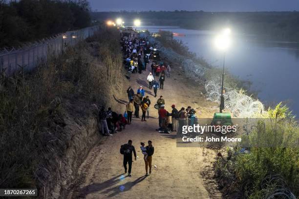 Seen from an aerial view, immigrants walk towards a U.S. Border Patrol transit center after wading through the Rio Grande from Mexico early on...