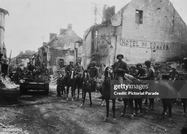 American military officers on horseback, horses captured from German troops, beside British tanks on a battle-scarred street - a sign for the Hotel...