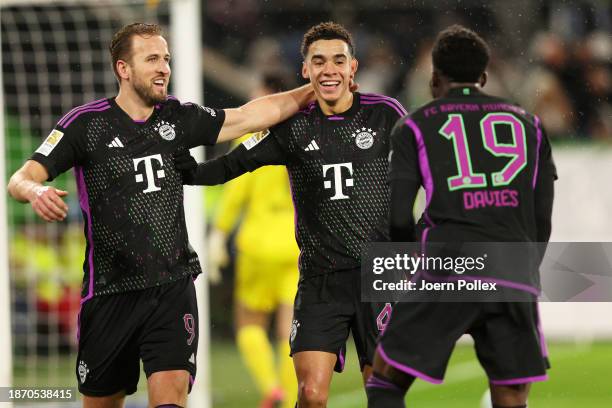 Jamal Musiala of Bayern Munich celebrates with teammates Harry Kane and Alphonso Davies after scoring their team's first goal during the Bundesliga...