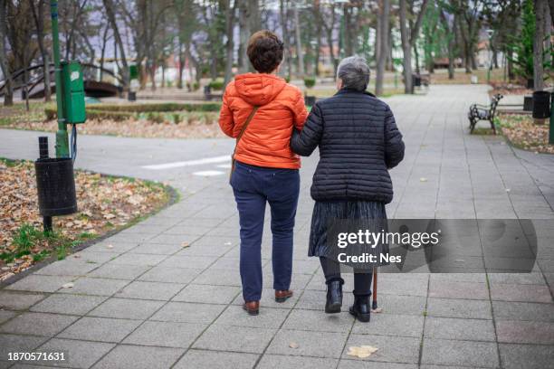 autumn decor in a public park, mother and daughter walking in the park - senior women walking stock pictures, royalty-free photos & images