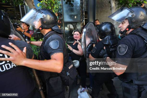 Person shouts as police officers stand guard during a demonstration against President Javier Milei and recent announcements by Minister of Economy...