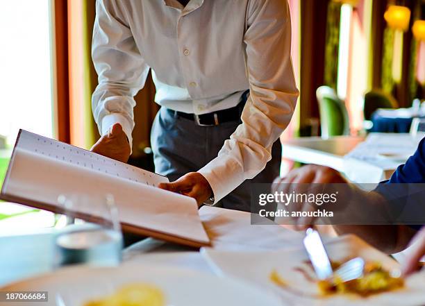 waiter in a restaurant showing wine - 餐牌 個照片及圖片檔