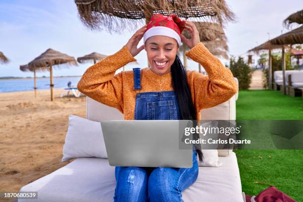 beautiful digital nomad colombian girl puts on santa's hat on christmas day to make a video conference with her family in colombia - colombia business breakfast meeting stock pictures, royalty-free photos & images