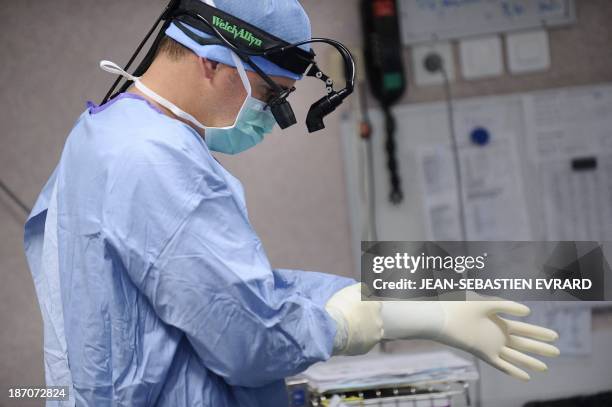 Surgeon puts on gloves before an open-heart surgery in a cardiac surgery unit at the CHU Angers teaching hospital in Angers, western France, on...