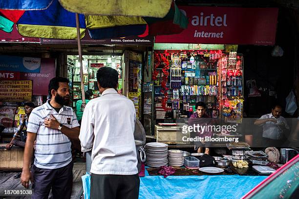 Vendor sits under signage for Bharti Airtel Ltd. At a store as a food stall vendor serves a customer in Kolkata, West Bengal, India, on Thursday,...