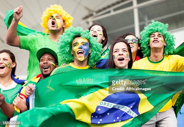 group of fans cheering brazil at a football match - a brazil supporter stock pictures, royalty-free photos & images