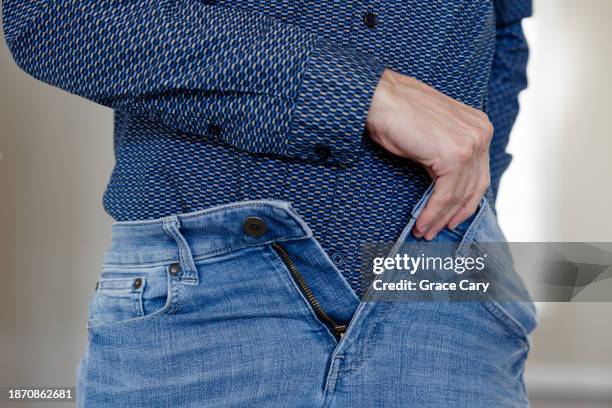 man tucks in his shirt while getting dressed - trousers stock pictures, royalty-free photos & images