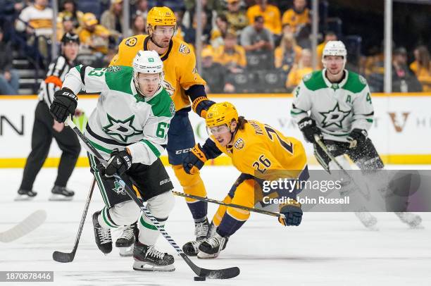 Evgenii Dadonov of the Dallas Stars skates against Philip Tomasino of the Nashville Predators during an NHL game at Bridgestone Arena on December 23,...
