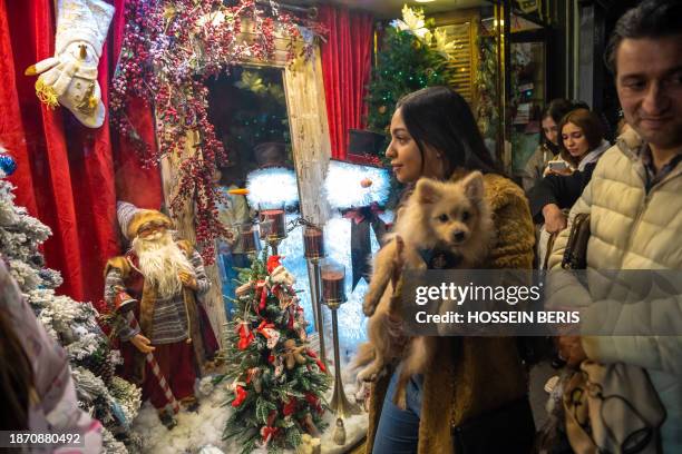 Tehran, Iran. Iranian women are standing in front of a shop decorated for Christmas shopping in downtown Tehran, Iran, on December 22, 2023. Iran's...