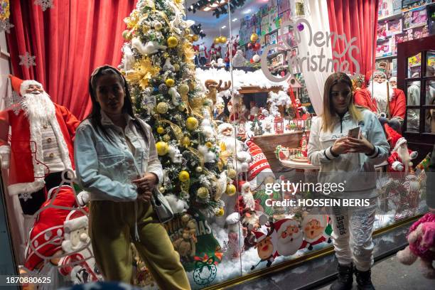 Tehran, Iran. Iranian women are standing in front of a shop decorated for Christmas shopping in downtown Tehran, Iran, on December 22, 2023. Iran's...