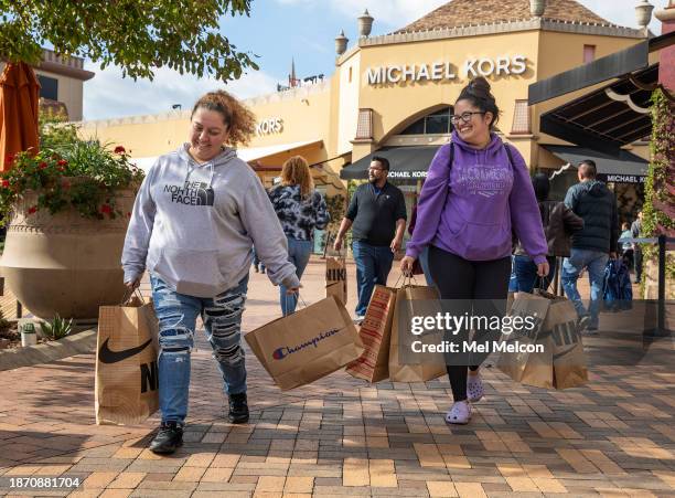 Mia Maagallanes, left, of Wilmington, and her friend Jennifer Ramirez of San Pedro make their way with Christmas gifts after shopping for family...