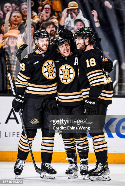 David Pastrnak of the Boston Bruins celebrates his first period goal with teammates, Pavel Zacha, and Parker Wotherspoon against the Minnesota Wild...