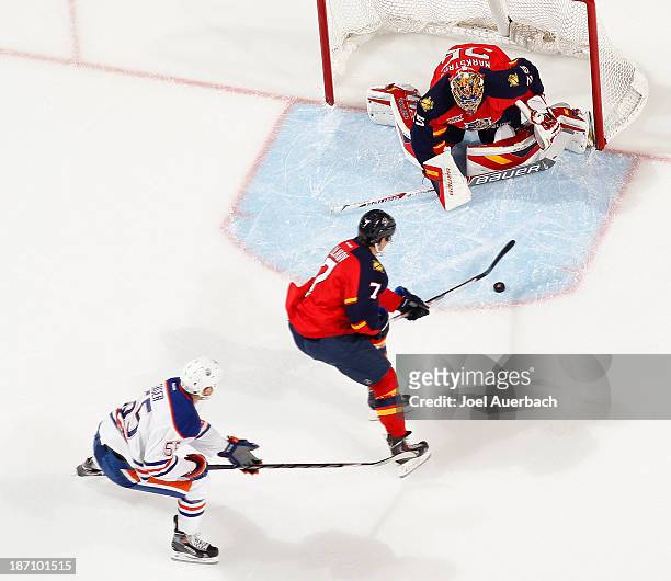 Dmitry Kulikov clears the puck from in front of goaltender Jacob Markstrom of the Florida Panthers as Ben Eager of the Edmonton Oilers trails the...