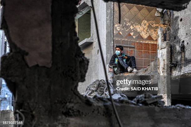 Boy looks on while sitting by a damaged wall in a building next to another destroyed by Israeli bombardment in Rafah in the southern Gaza Strip on...