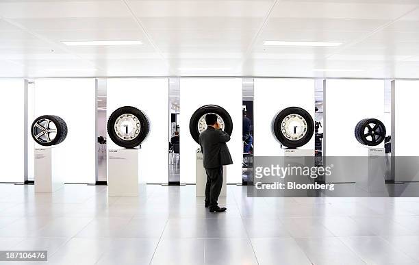 Visitor speaks on a mobile device as he stands beside a display of tires manufactured by Pirelli SpA, following a news conference in London, U.K. On...