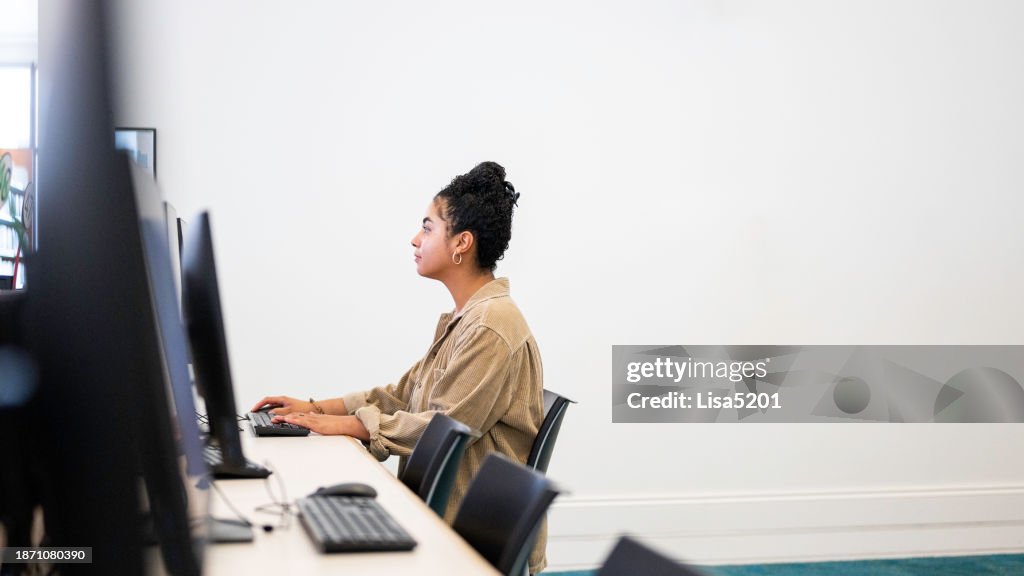 Mixed race young woman uses a desktop computer at a public library or on a university campus