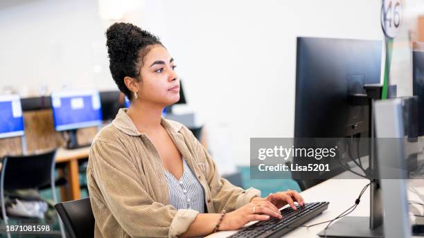 mixed race young woman uses a desktop computer at a public library or on a university campus - public library stock pictures, royalty-free photos & images
