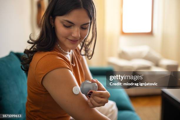 woman applying glucose sensor on arm - diabetes typ 2 bildbanksfoton och bilder