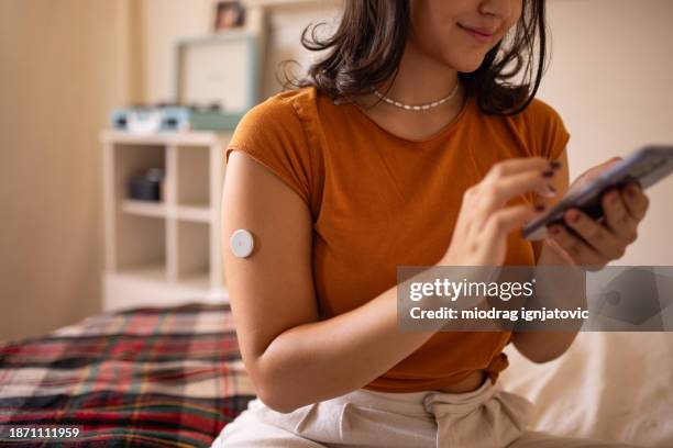 teenager sitting on bed - continuous glucose monitor stock pictures, royalty-free photos & images