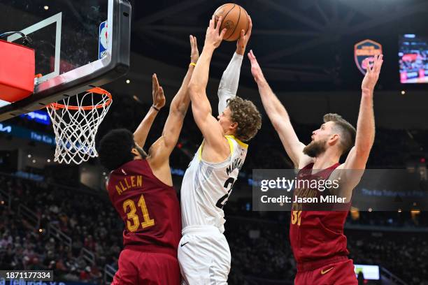 Lauri Markkanen of the Utah Jazz shoots over Jarrett Allen and Dean Wade of the Cleveland Cavaliers during the third quarter at Rocket Mortgage...