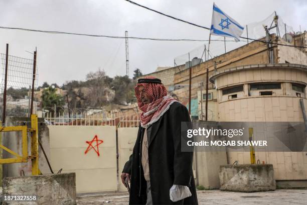 Palestinian man walks past an Israeli checkpoint in the city of Hebron in the occupied West Bank on December 24, 2023.