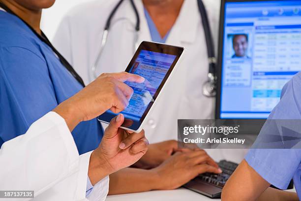 doctors using digital tablet together in hospital - informe-médico-electrónico fotografías e imágenes de stock