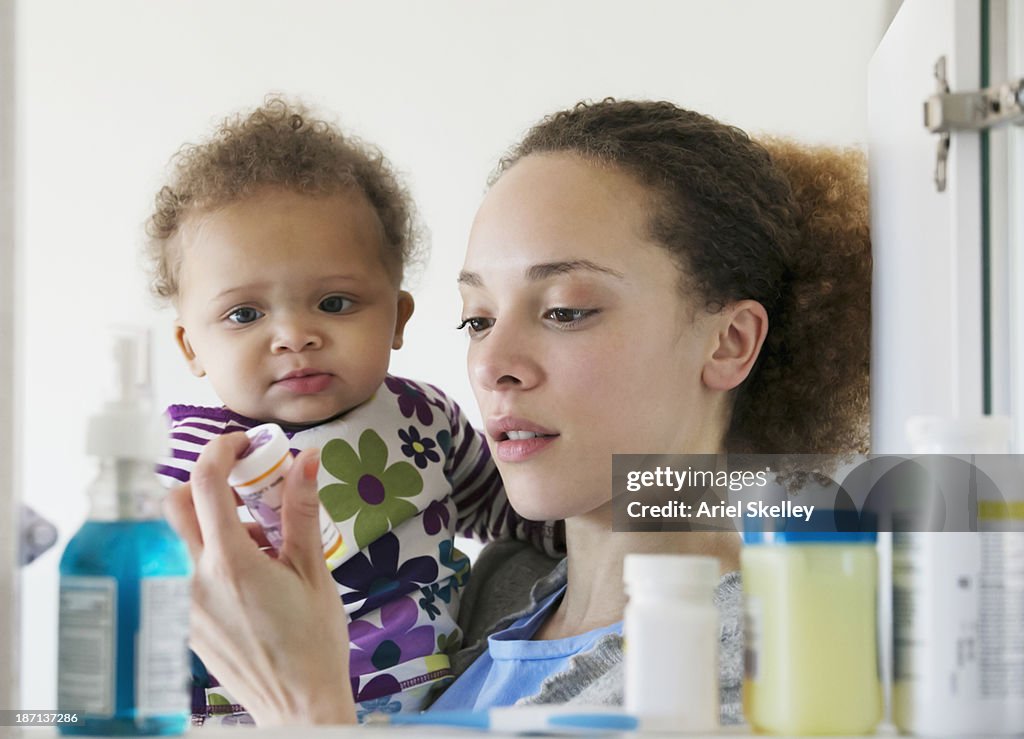 Black mother with baby reading pill bottle