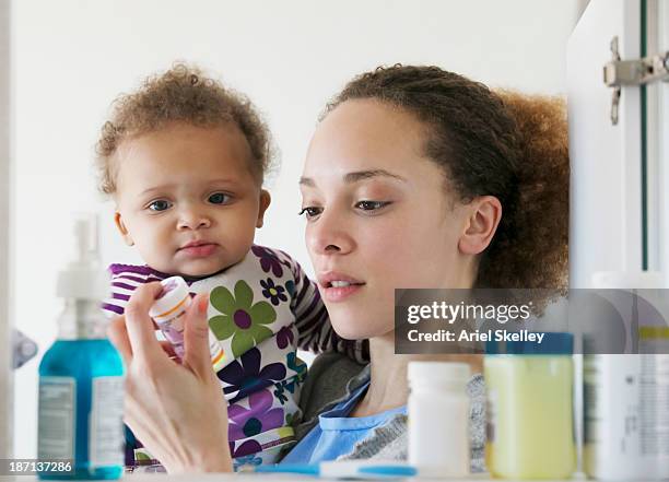 black mother with baby reading pill bottle - armoire de toilette photos et images de collection
