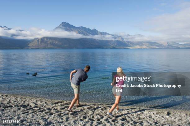 caucasian couple skipping stones on rural lake - skimming stones stock pictures, royalty-free photos & images