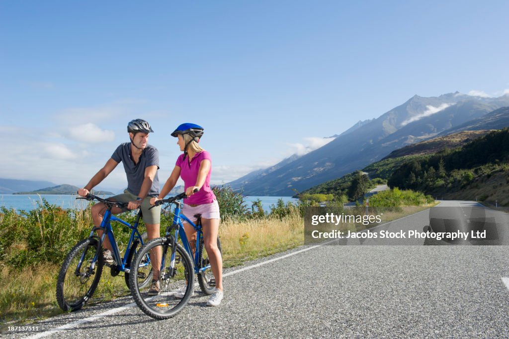 Caucasian couple riding bicycles on rural road
