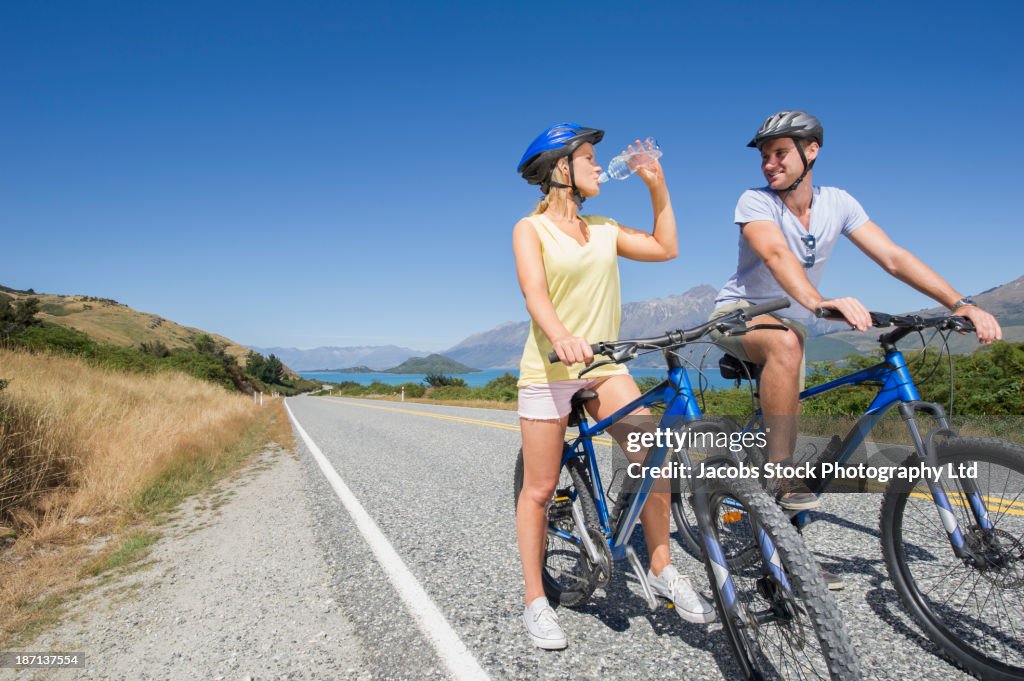 Caucasian couple riding bicycles on rural road