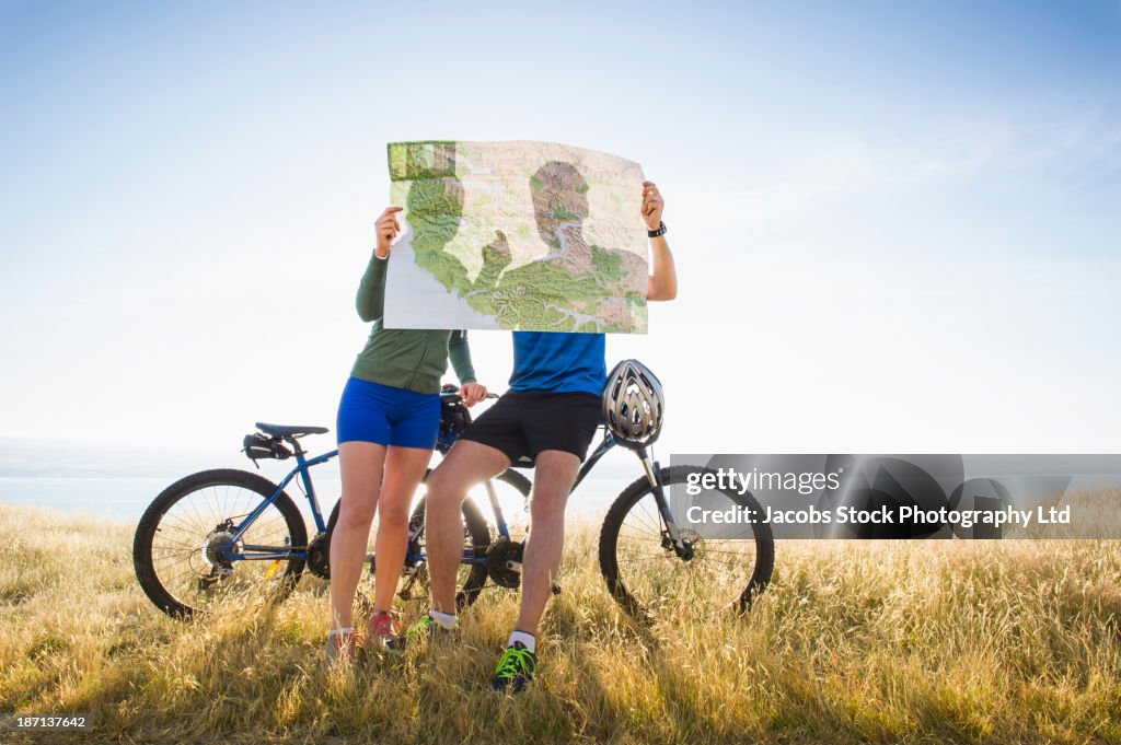 Caucasian couple reading map in rural landscape