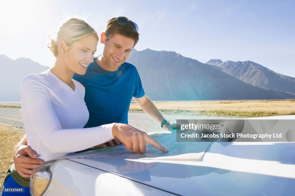 Caucasian couple reading map in rural landscape
