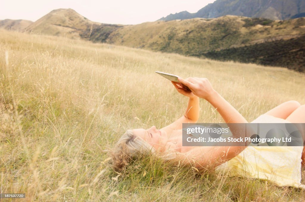 Caucasian woman using digital tablet in tall grass