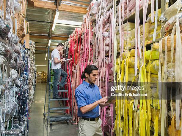 workers examining fabric in textile factory - scompartimento di immagazzinaggio foto e immagini stock
