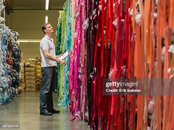 Caucasian worker examining fabric in textile factory