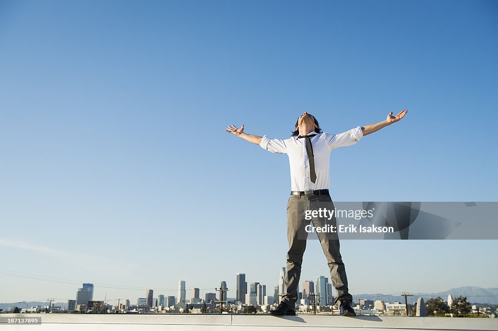 Mixed race businessman standing on urban rooftop