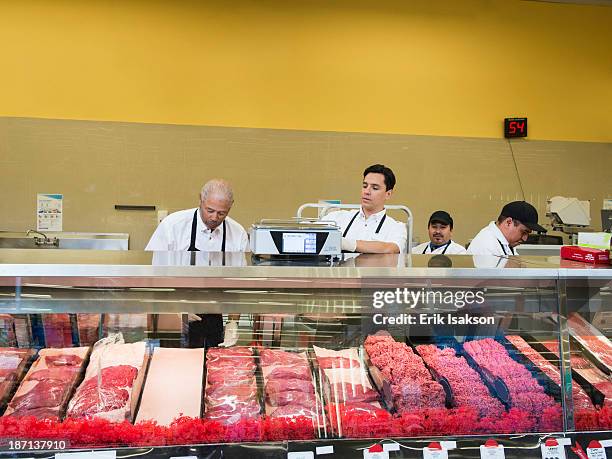 butchers at meat counter of grocery store - präsentation hinter glas stock-fotos und bilder