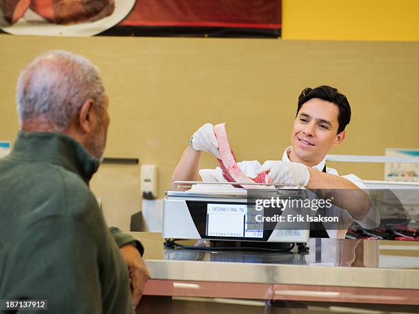 butcher serving customer meat counter of grocery store - beefsteak 2013 stock pictures, royalty-free photos & images