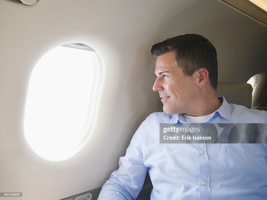 Caucasian businessman looking out airplane window