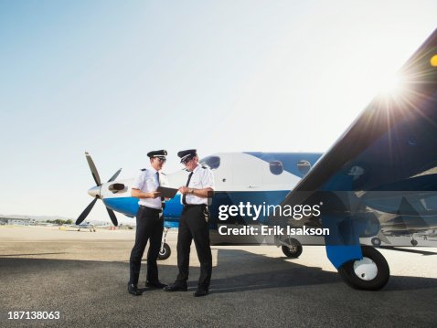 Caucasian pilots using digital tablet on runway Caucasian pilots using digital tablet on runway