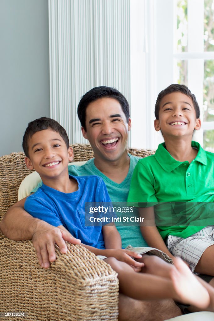 Hispanic father and sons sitting in armchair