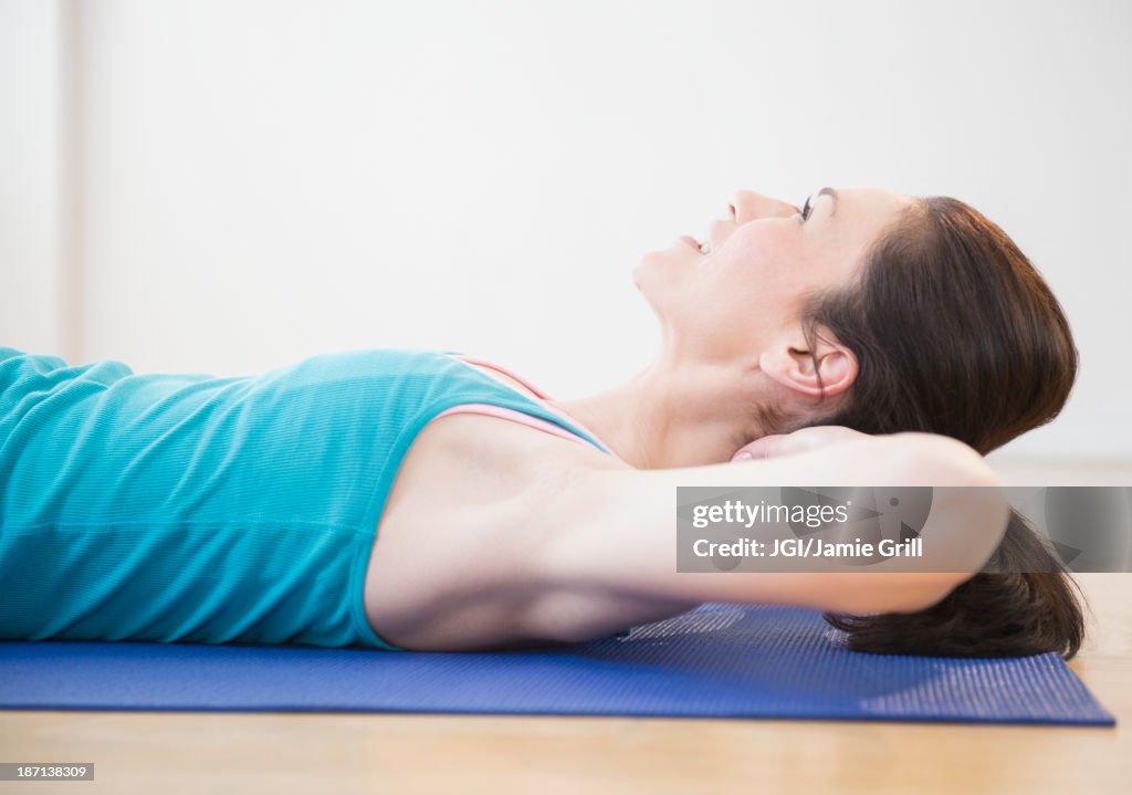 Caucasian woman laying on yoga mat