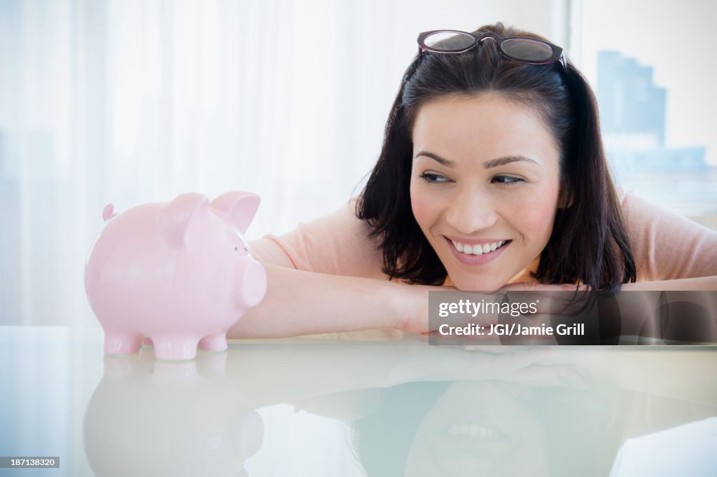 Caucasian woman examining piggy bank
