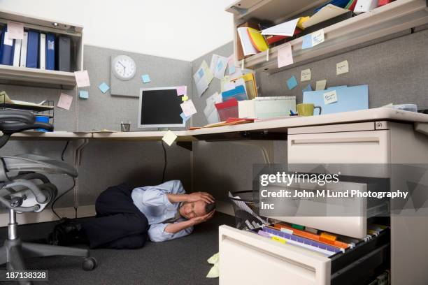 businessman crying under cubicle desk - foetushouding stockfoto's en -beelden