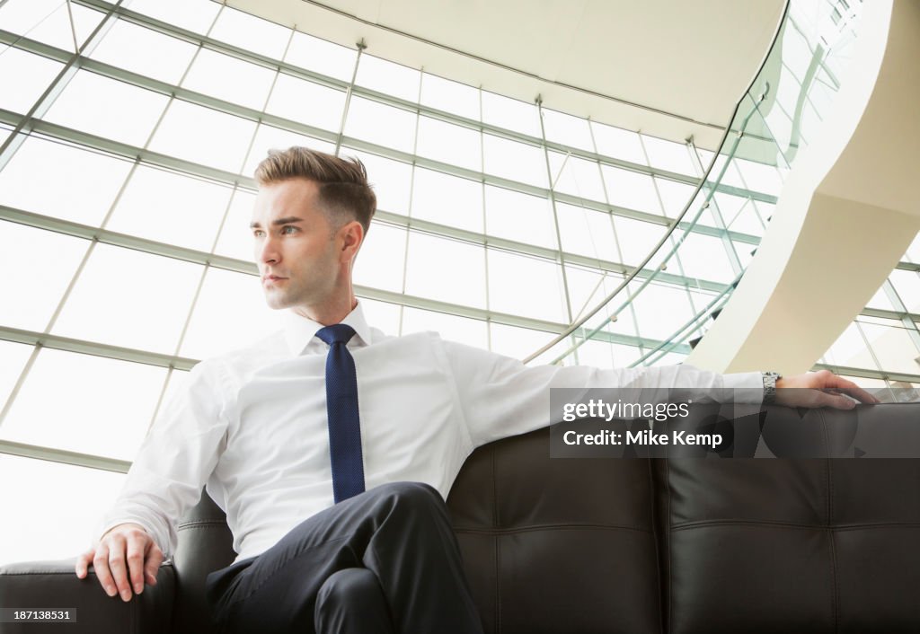 Caucasian businessman sitting on sofa in lobby