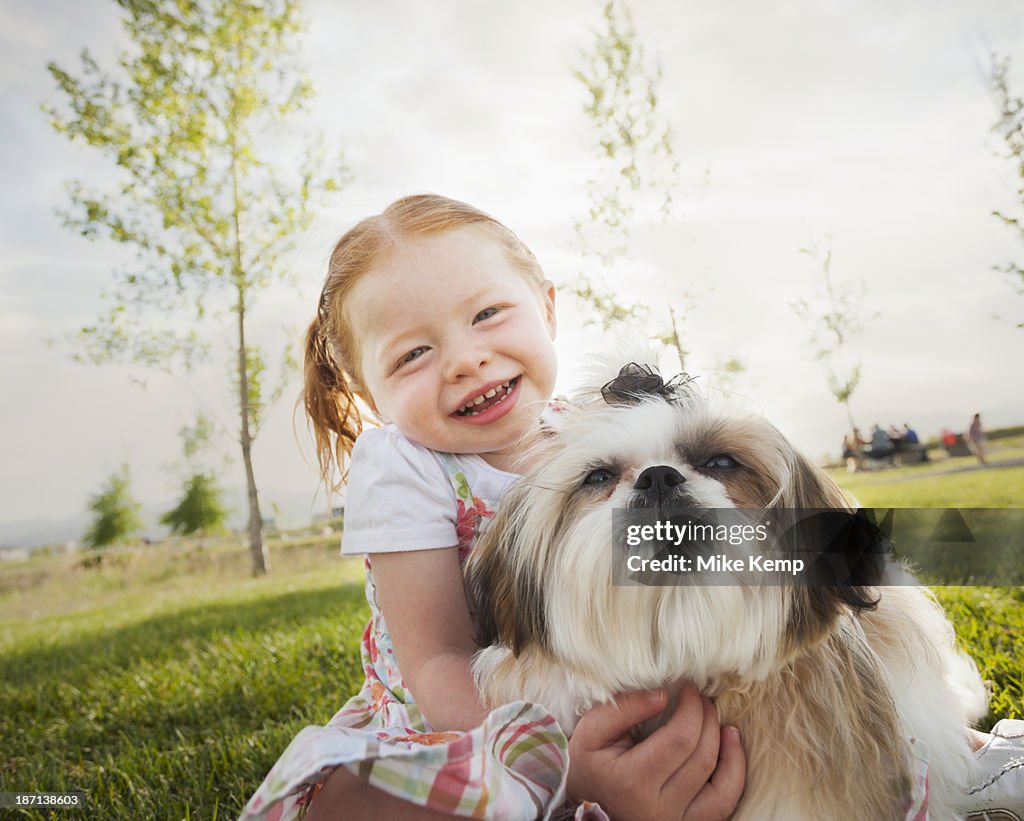 Caucasian girl hugging dog in grass
