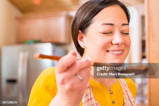 mixed race woman cooking in kitchen - smelling food stock pictures, royalty-free photos & images