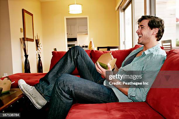 caucasian man eating take out food on sofa - feet up tv stock pictures, royalty-free photos & images