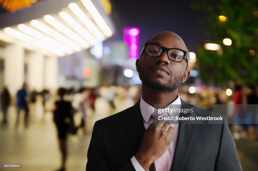 Black businessman adjusting tie on city street